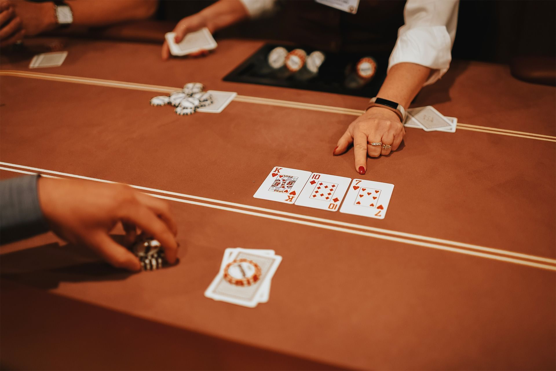 Poker hand showing a king, ten, and seven of hearts by betting chips and playing cards on a felt table at The Brook
