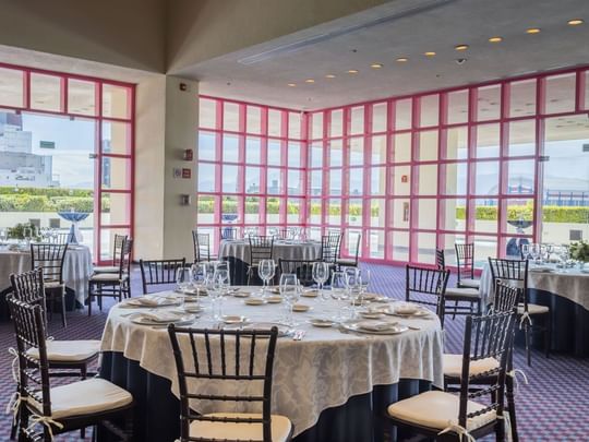 Terraza Virreyes with round tables, white linens, and pink-framed glass walls at Camino Real Polanco Mexico