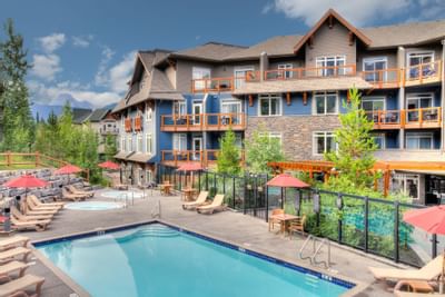 Exterior view of Blackstone Mountain Lodge with outdoor pool and sun loungers, surrounded by lush greenery