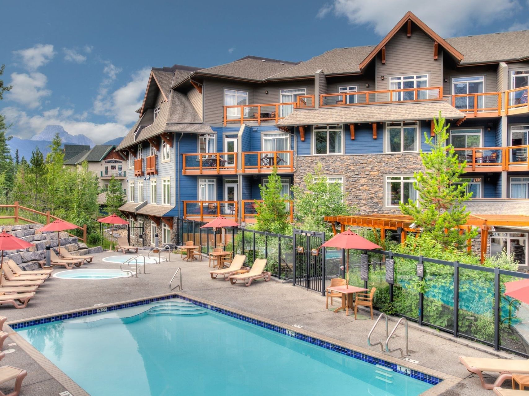 Exterior view of Blackstone Mountain Lodge and outdoor pool with sun loungers, surrounded by greenery