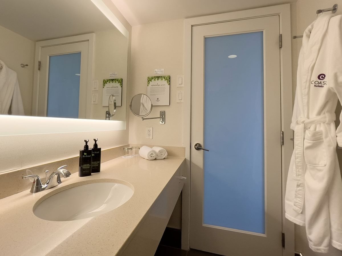 Hotel guestroom washroom with sink and bathrobe