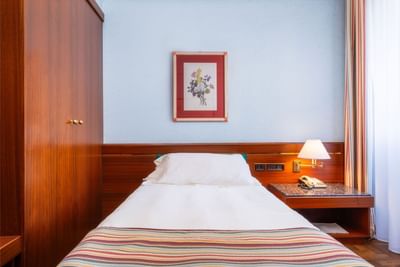 Comfy bed, cupboard & bedside table with lamp in Business Room at Hotel Crivi's in Milan