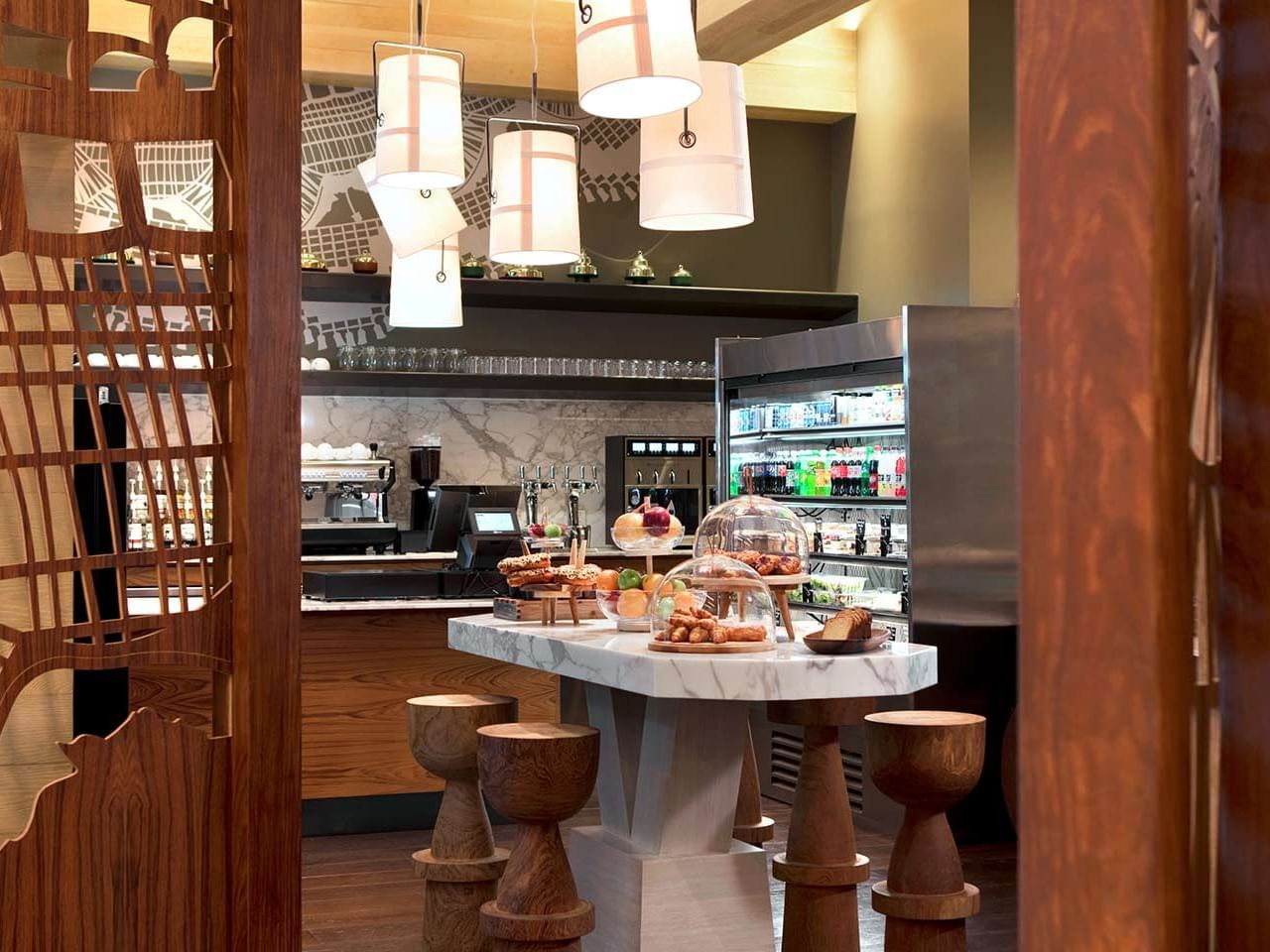 Interior of Seafire Pantry featuring a marble table, wooden stools & display of pastries on The Residences at Seafire.