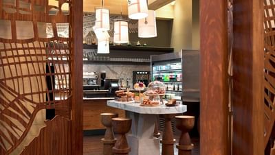 Seafire Pantry with a marble table of pastries, wooden stools, and a stocked beverage fridge at The Residences at Seafire