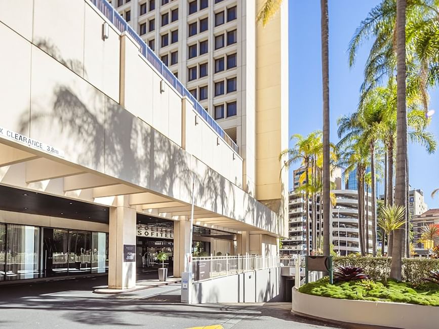 Entrance of the Sofitel Brisbane Central Hotel with palm trees and clear blue sky
