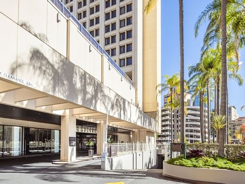 Entrance of the Sofitel Brisbane Central Hotel with palm trees and clear blue sky