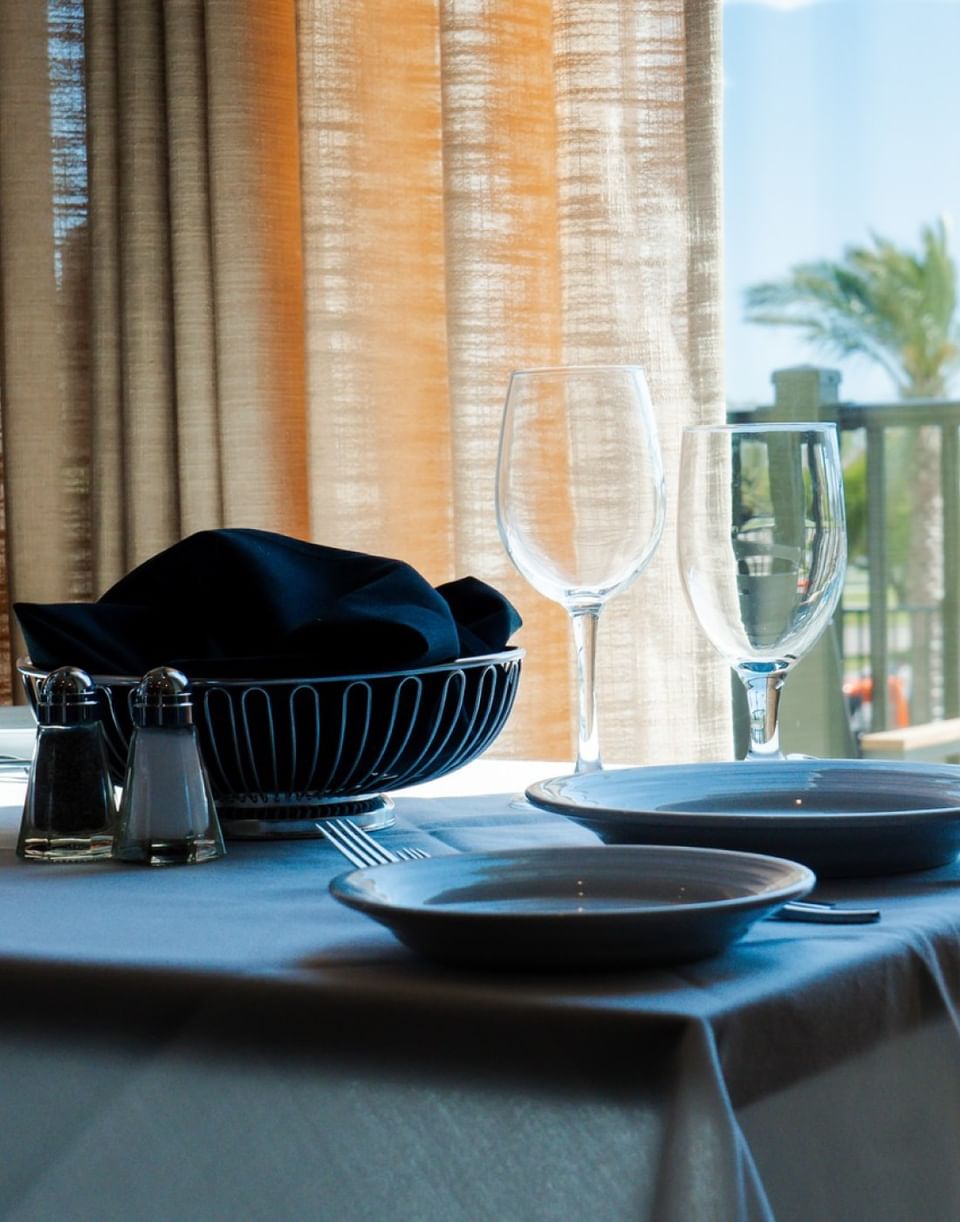 The Library restaurant table setting with wine glasses, white plates, and a black napkin at The Markham Hotel