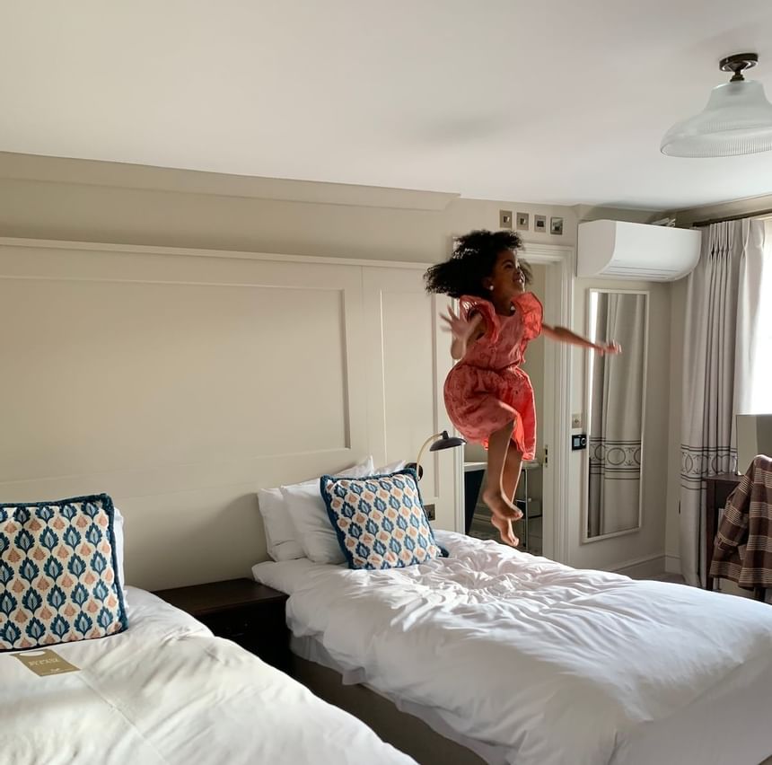 A girl jumping on the bed in a room at Richmond Hill Hotel