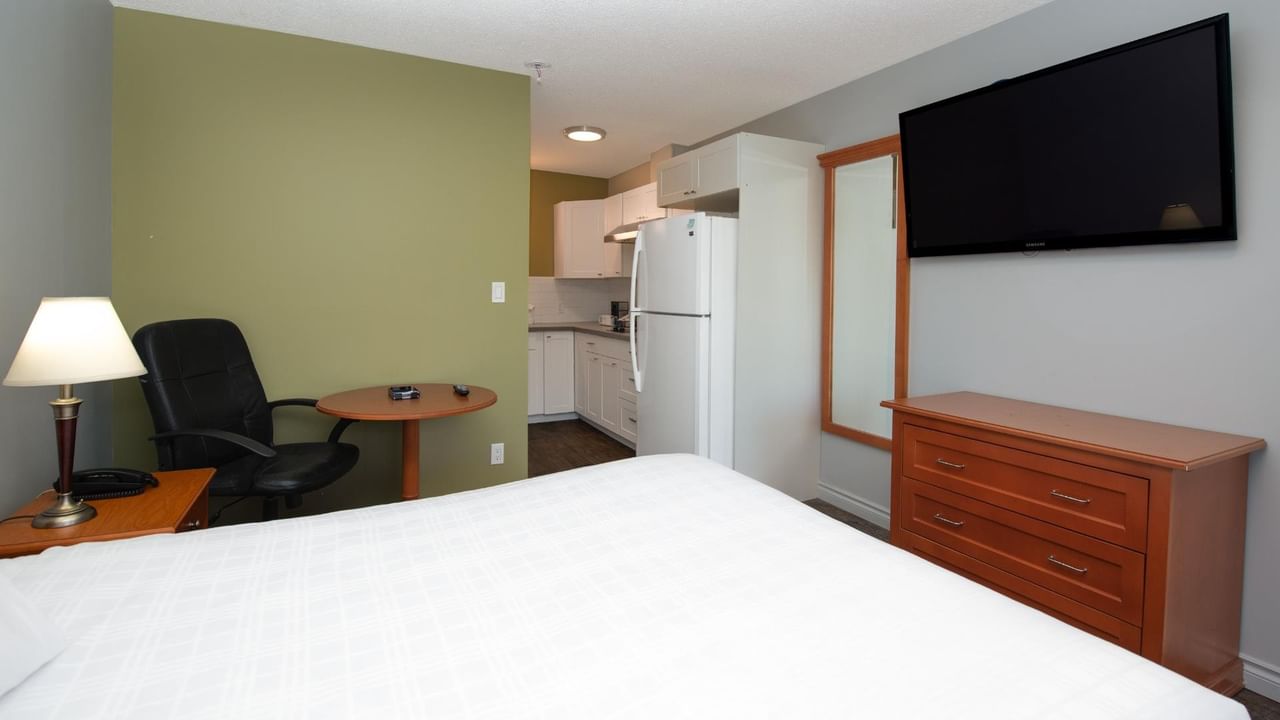 Guest room at Coast Red Deer Hotel with queen bed, desk, TV and full-size fridge