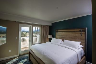 A hotel bedroom at The Stanley Hotel with a modern farmhouse bed and a private balcony with a beautiful view