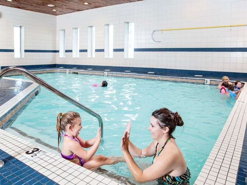 Mother and daughter playing in indoor swimming pool