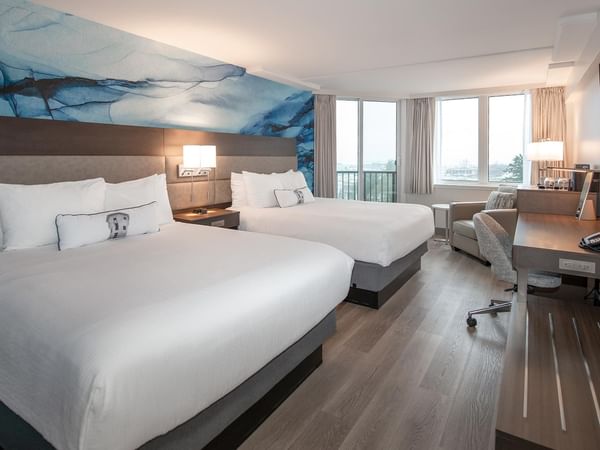 Two queen beds in a room with a desk and chair at Coast Bastion Hotel in Nanaimo.