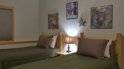 A comfortable bedroom at The Stanley Hotel with two twin beds and wood frame headboards, decorated with art