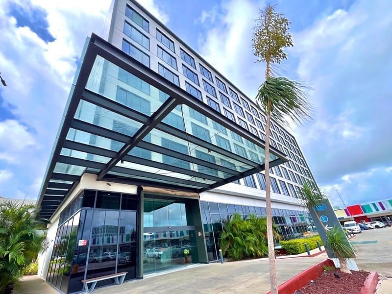 Fiesta Inn Express Cancun Cumbres exterior featuring a striking glass-covered entrance and dark metal framing