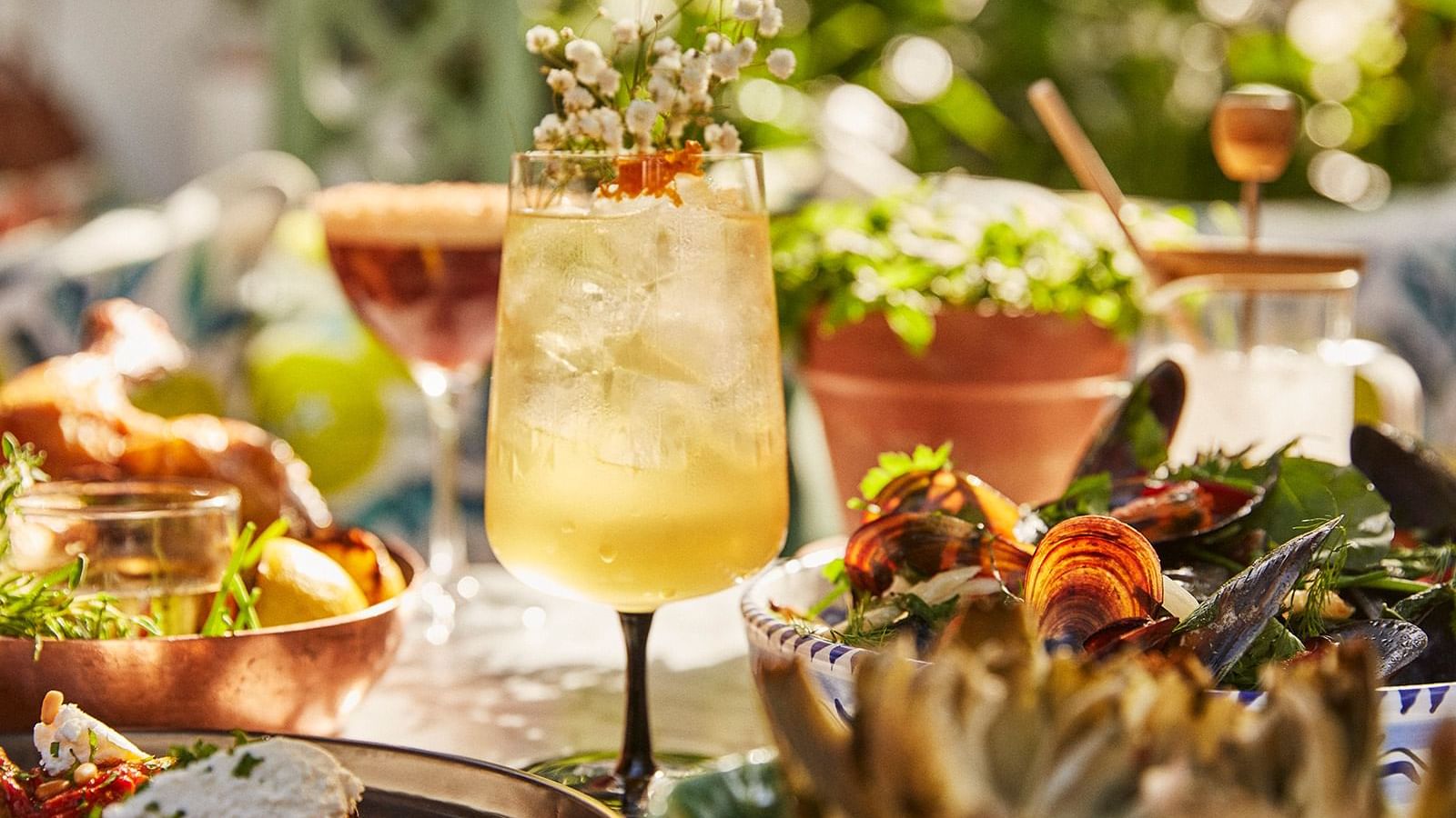 Tall cocktail glass with white flowers, placed next to a bowl of fresh seafood at the Marbella Club
