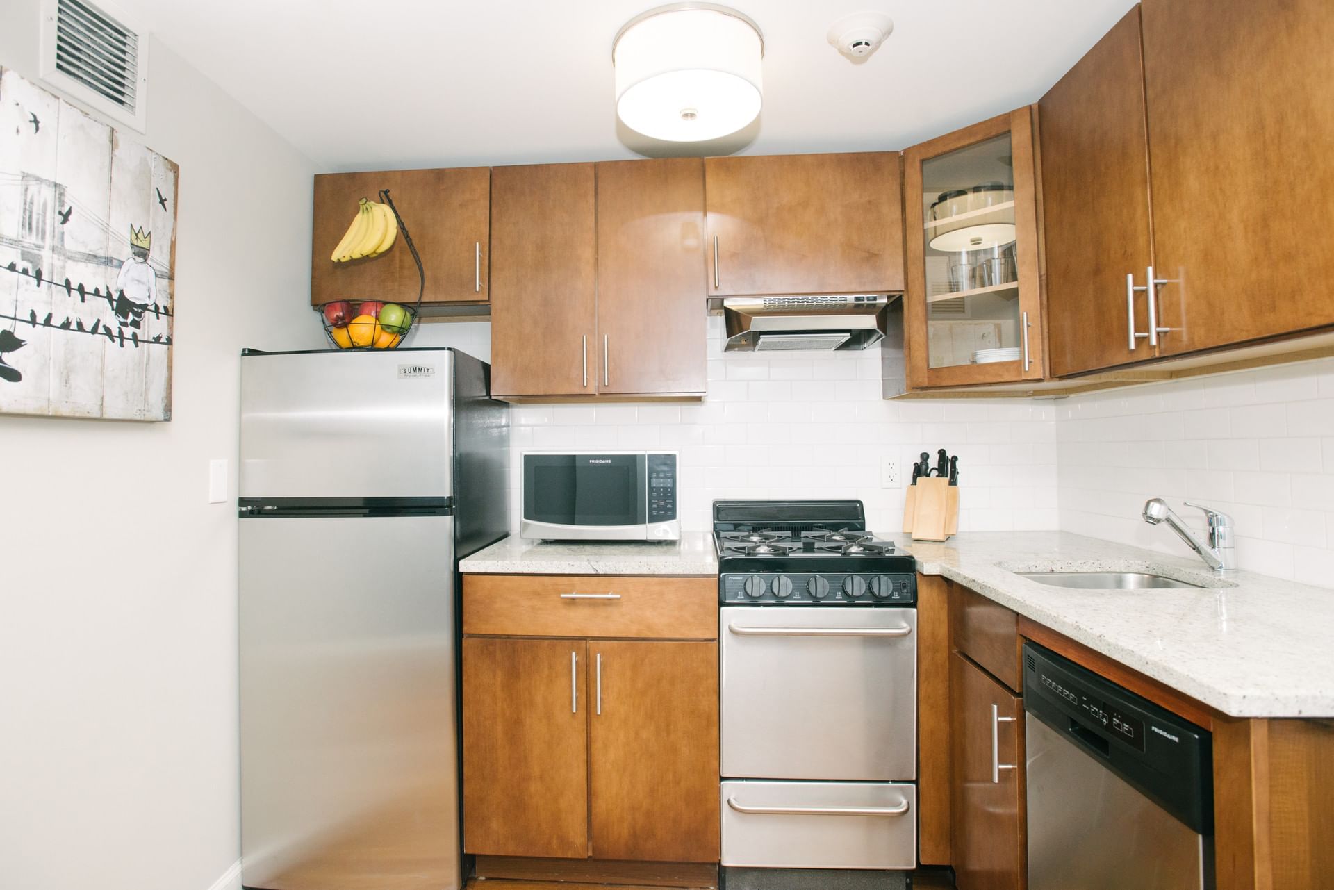 A compact kitchen with wood cabinets, stainless steel appliances, and a small countertop.