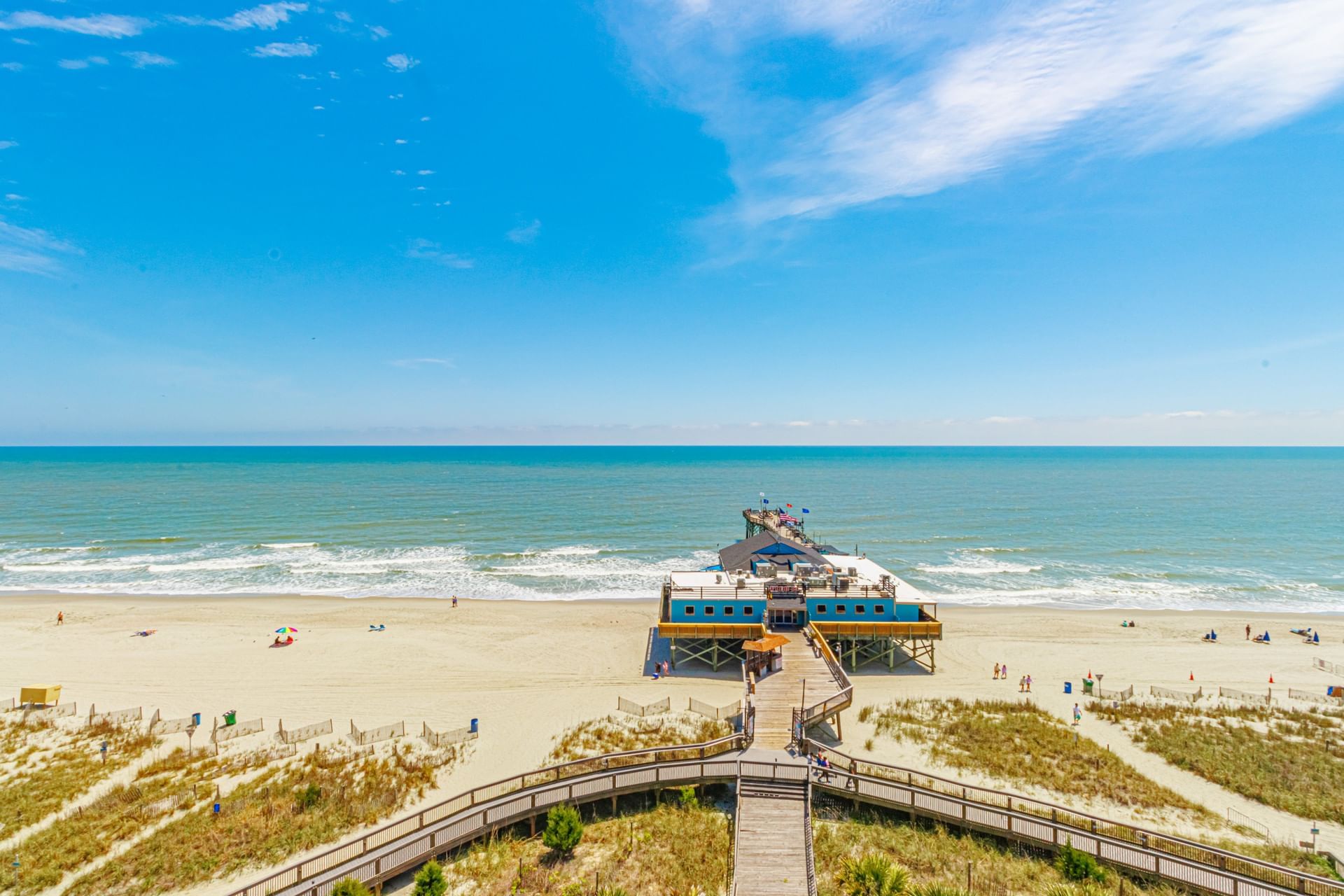 A beach with a pier and boardwalk leading to the ocean.