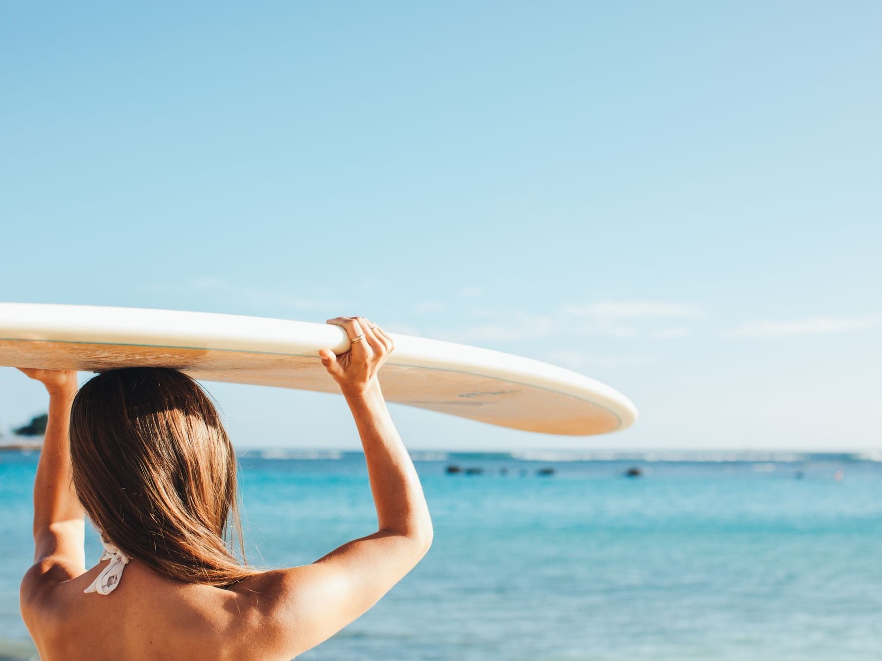 Girl holding a surfboard on the beach near Stay Hotel Waikiki