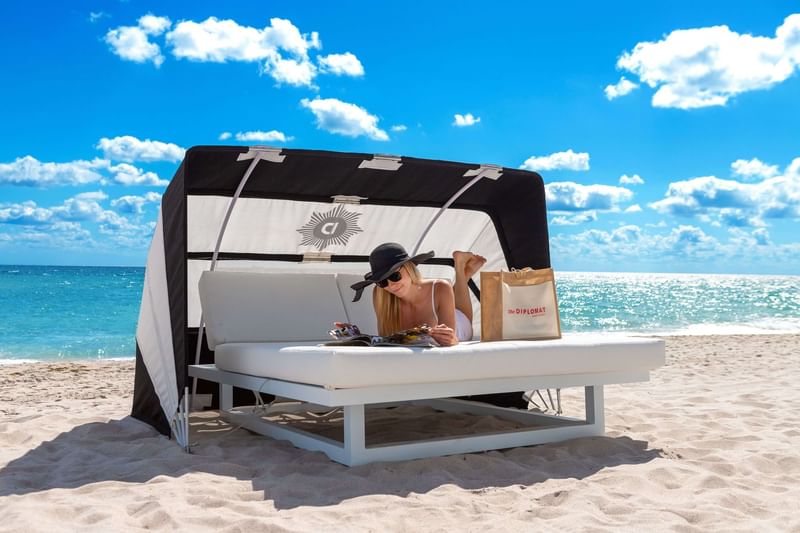 Lady lounging on a beach cabana by the sea near Diplomat Beach Resort