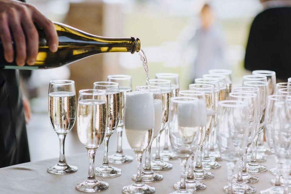 Server pouring sparkling wine into glasses for a lively wedding reception near The Met Hotel Leeds, England