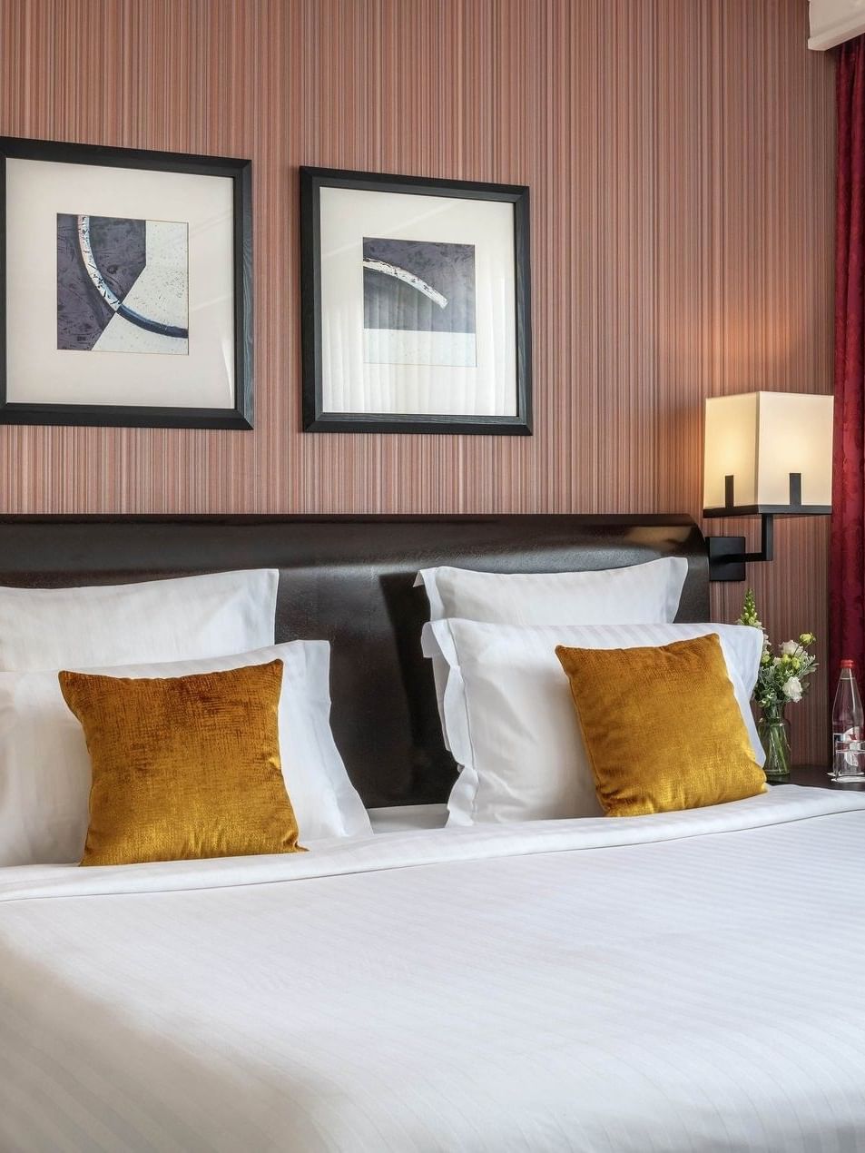 Plush bed with gold pillows by black nightstands under modern square art in Deluxe Room at Warwick Paris Champs Elysées