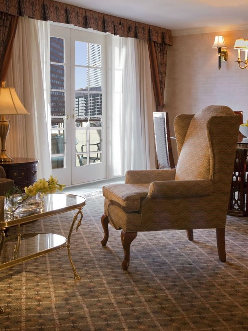 Wingback chair by a gold coffee table under a chandelier in Presidential Suite at Warwick Denver