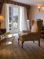 Wingback chair by a gold coffee table under a chandelier in Presidential Suite at Warwick Denver