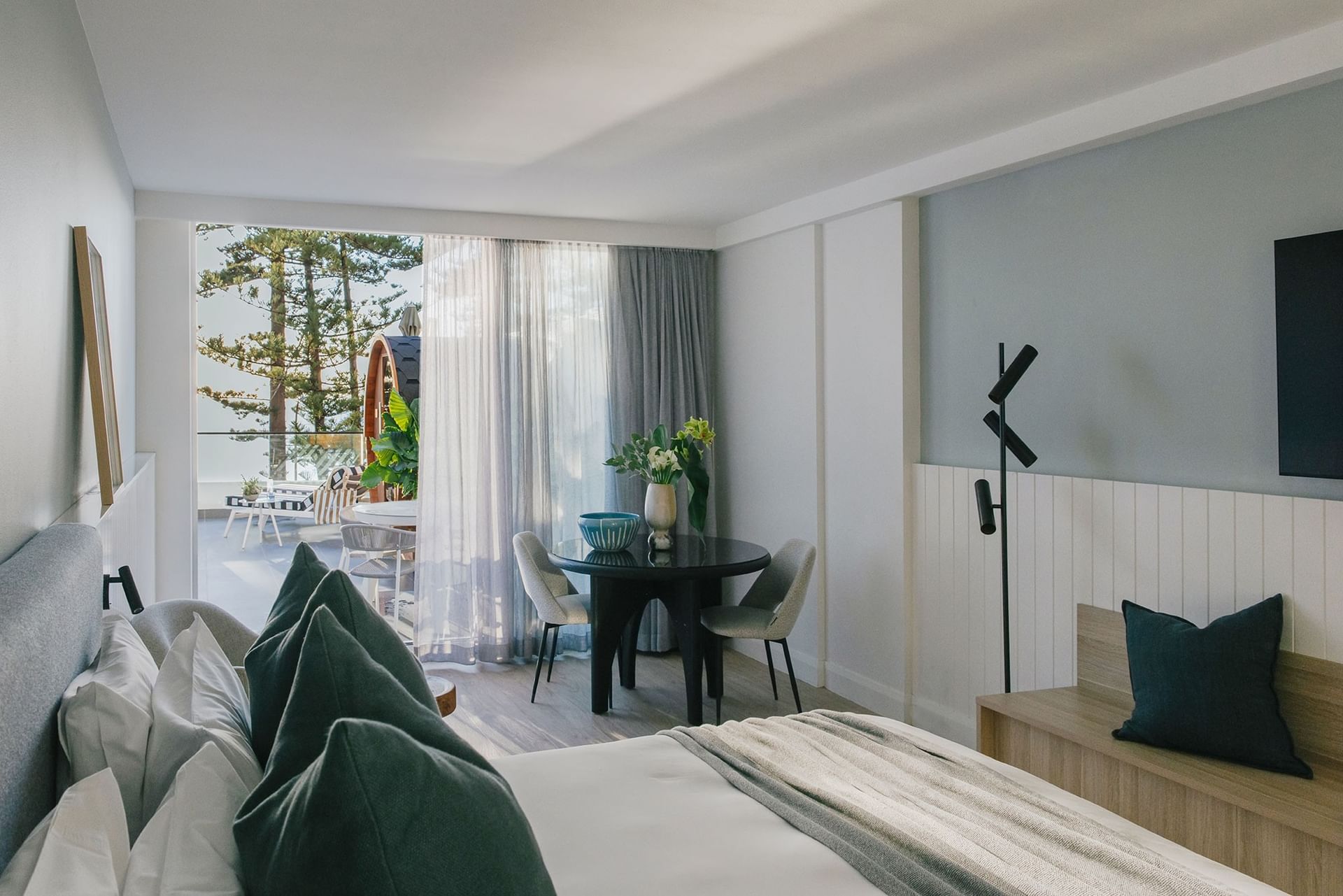 Bedroom with a round table by the curtains overlooking the balcony at Elysium Hotels, an elite hotel in Neutral Bay, Sydney