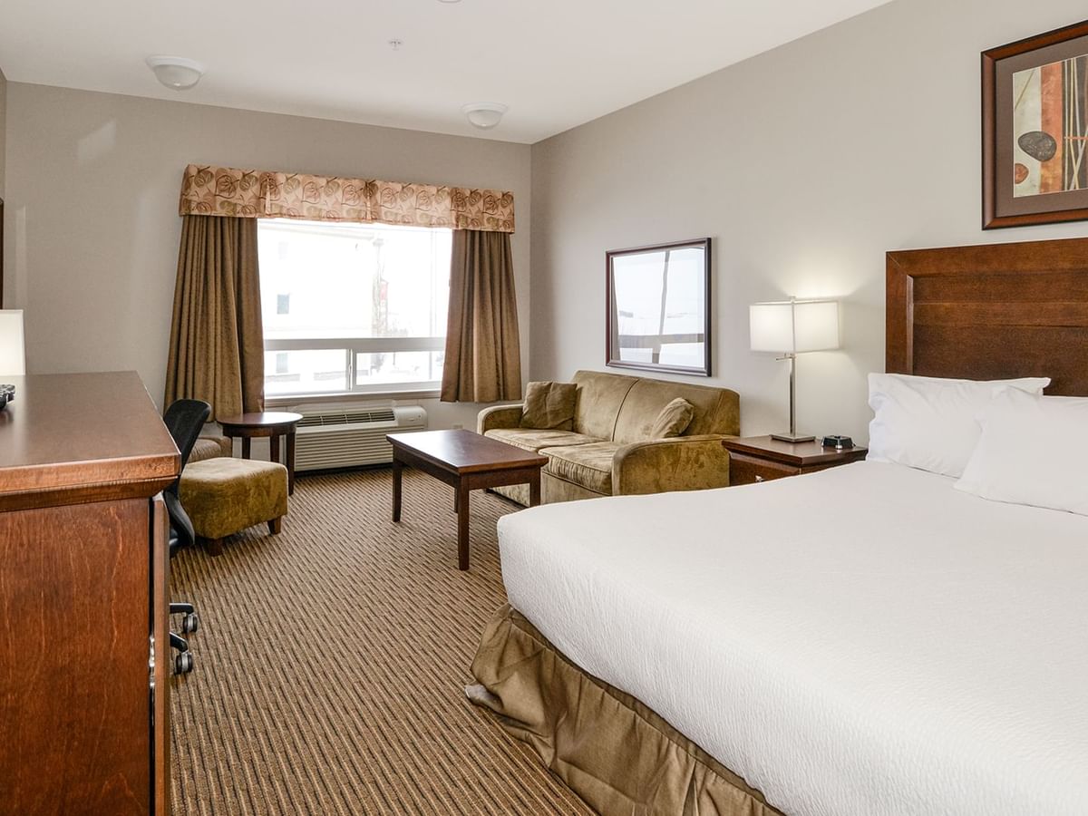 Hotel room with a king bed and a sofa bed, TV, work desk, chair, and coffee table