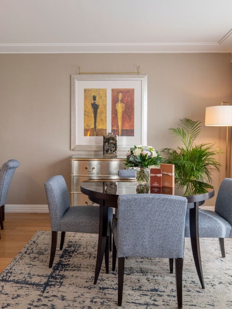 Gray chairs surrounding a round table by a desk in The Champs-Élysées Suite at Warwick Paris Champs Elysées
