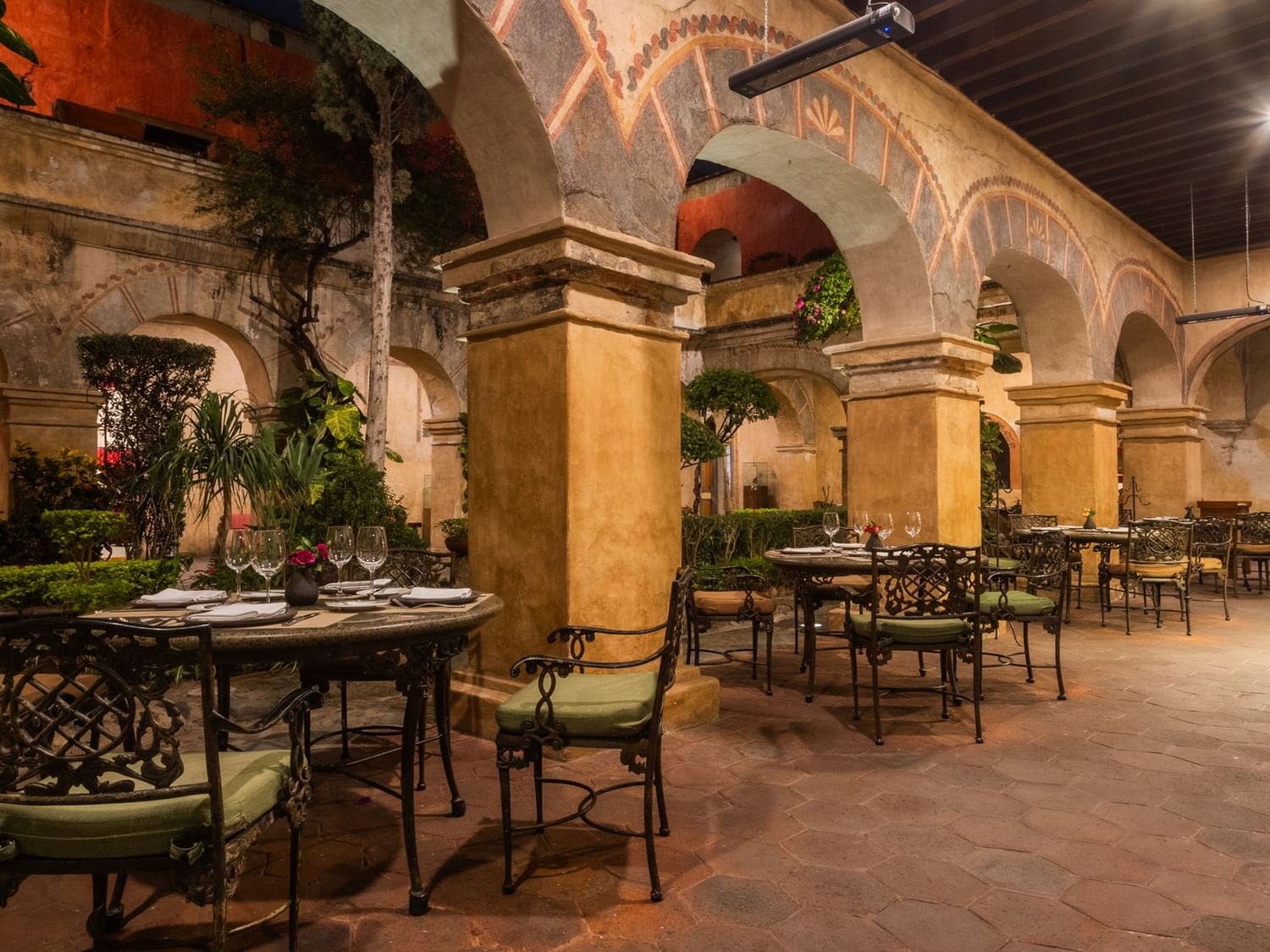 Dining area with tables and chairs under arches at El Refectorio in Quinta Real Oaxaca, Oaxaca de Juarez.