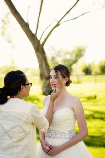 Bride getting her makeup touched up outdoors surrounded by the greenery at The Ranch at Ucross