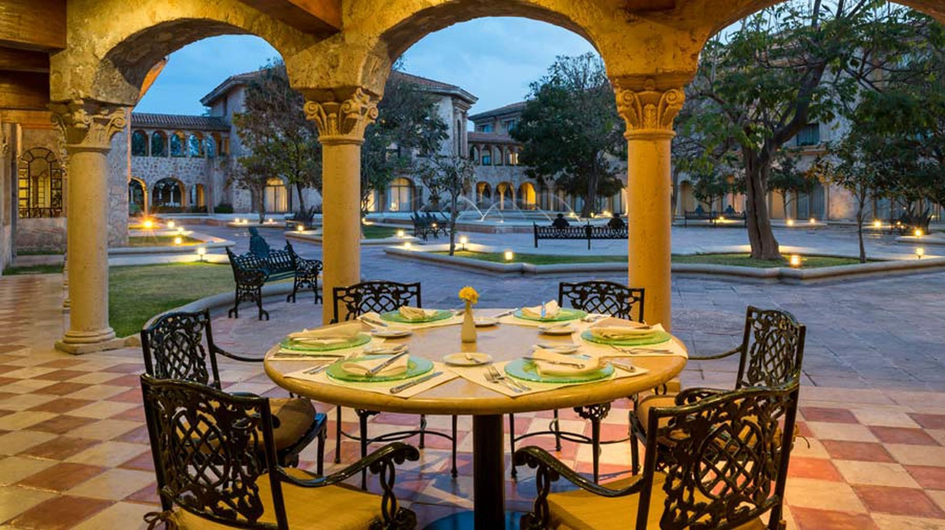 Los Murales outdoor dining table set for a meal featuring classic stone archways at Quinta Real Aguascalientes