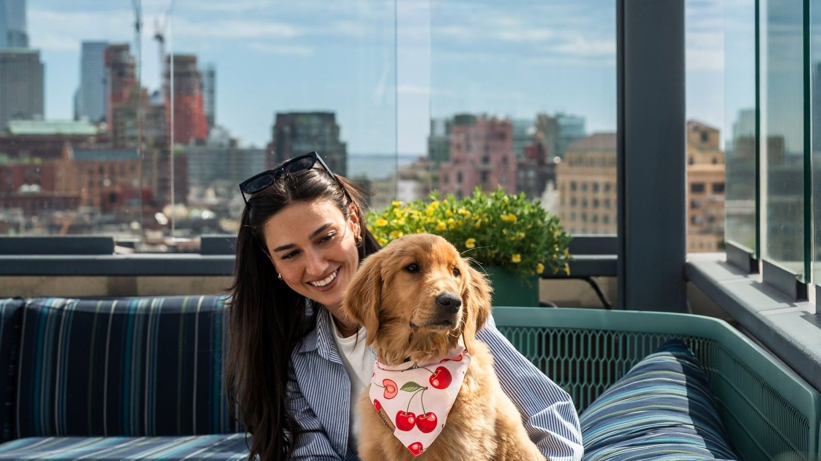 Smiling woman hugging puppy on outdoor lounge sofa at Gansevoort Meatpacking NYC, offering special Manhattan hotel deals
