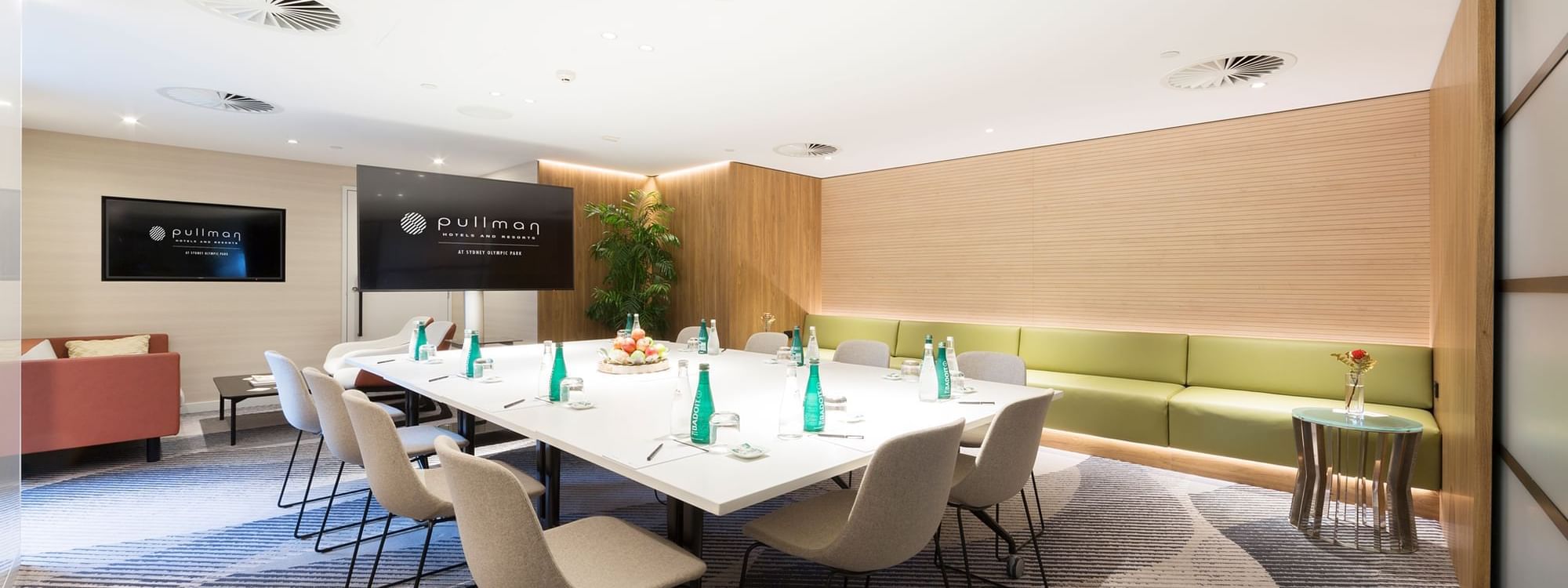 Lounge area & boardroom table arrangement for a Meeting with a wide screen at Pullman Sydney Olympic Park
