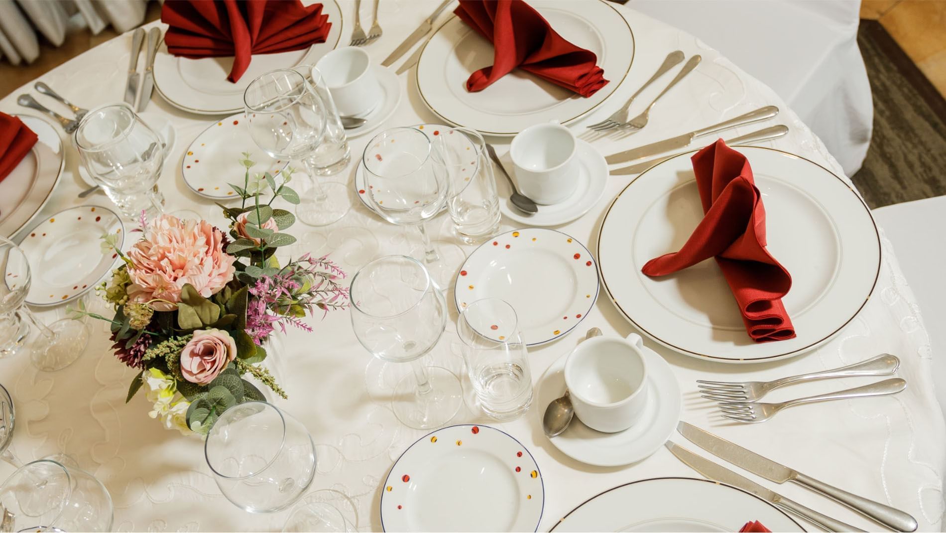 Formal table setting with red napkins and floral arrangements at Quinta Real Guadalajara