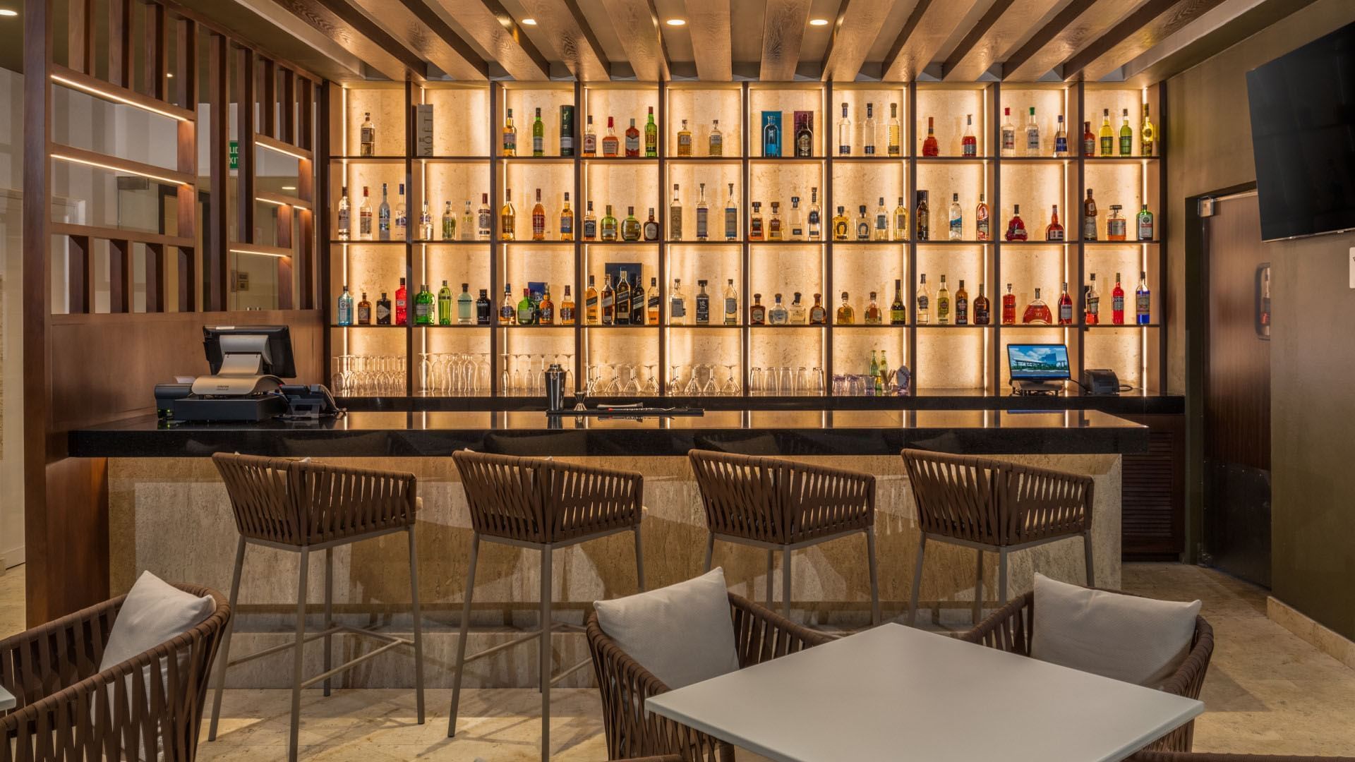 Peninsula Bar bar with rows of spirits and comfortable woven barstools at Camino Real Merida