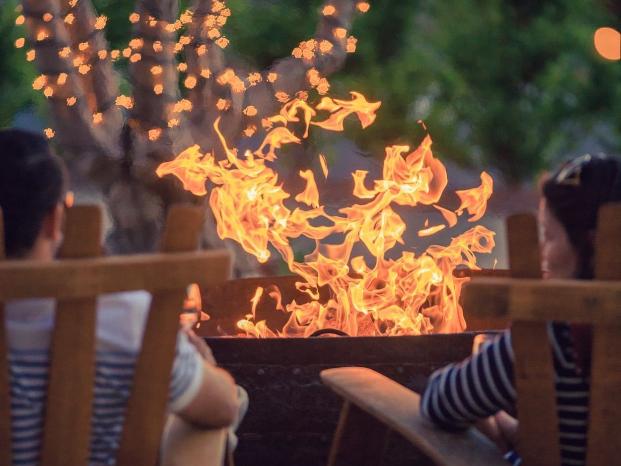 A couple sitting in front of a fire pit