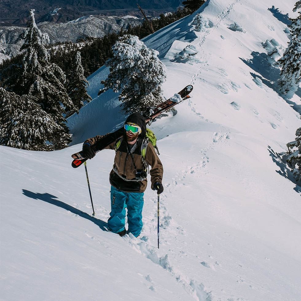 Skier climbing a mountain holding ski near Falkensteiner Hotels