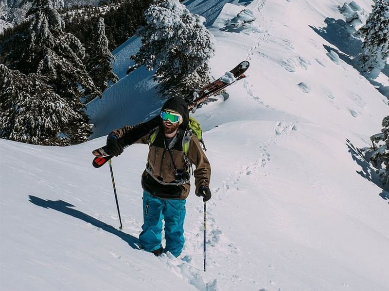 Skier climbing a mountain holding ski near Falkensteiner Hotels