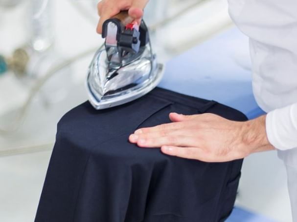 Man ironing a trouser featuring the Guest Laundry at Pensativo House Hotel
