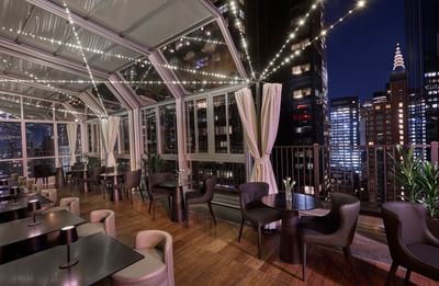 Upstairs at The Kimberly dining space with dark tables and brown chairs under string lights at night at The Kimberly Hotel