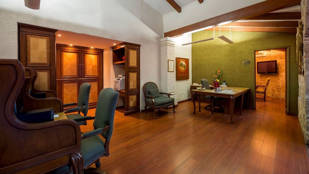 Classic business center featuring wooden desks and green armchairs at Quinta Real Guadalajara