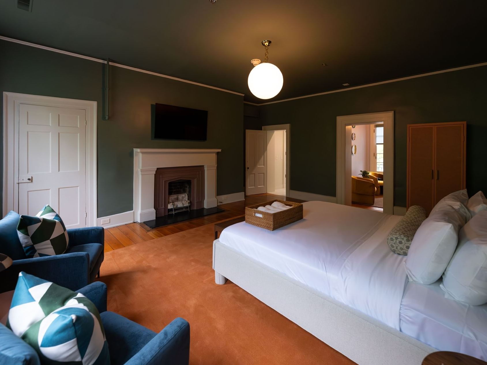 Luxury King Suite with a bed, armchairs, & a fireplace at The Ashbrook Hotel, featuring hotel room booking in Kentucky.