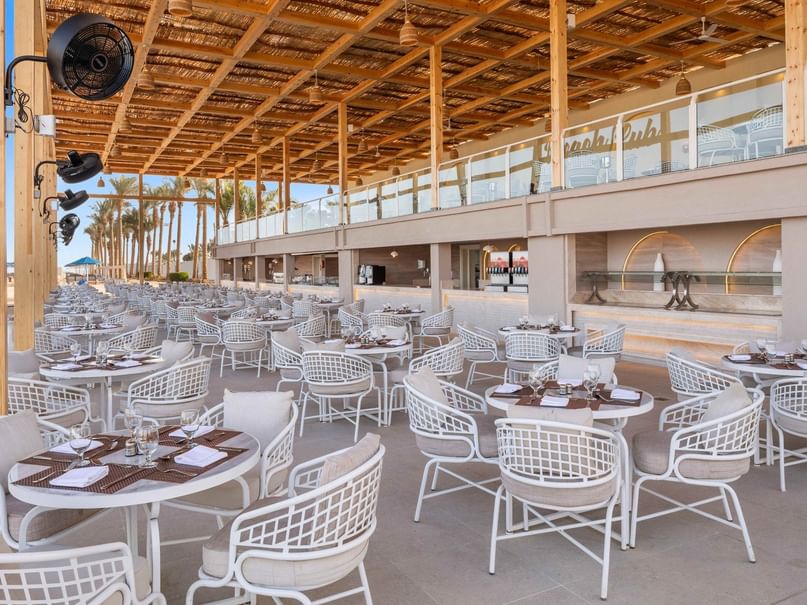 Spacious outdoor dining area with white tables and chairs under a wooden pergola at Pickalbatros Dana Beach Resort Hurghada