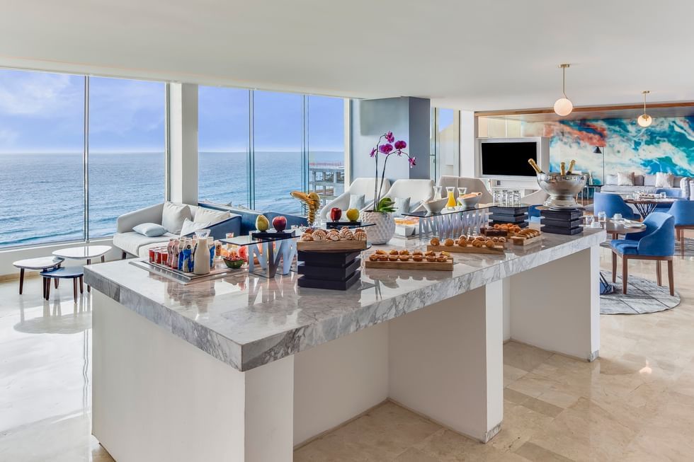 Table arranged with buffet overlooking the sea in a room with seating at Live Aqua Resorts and Residence Club