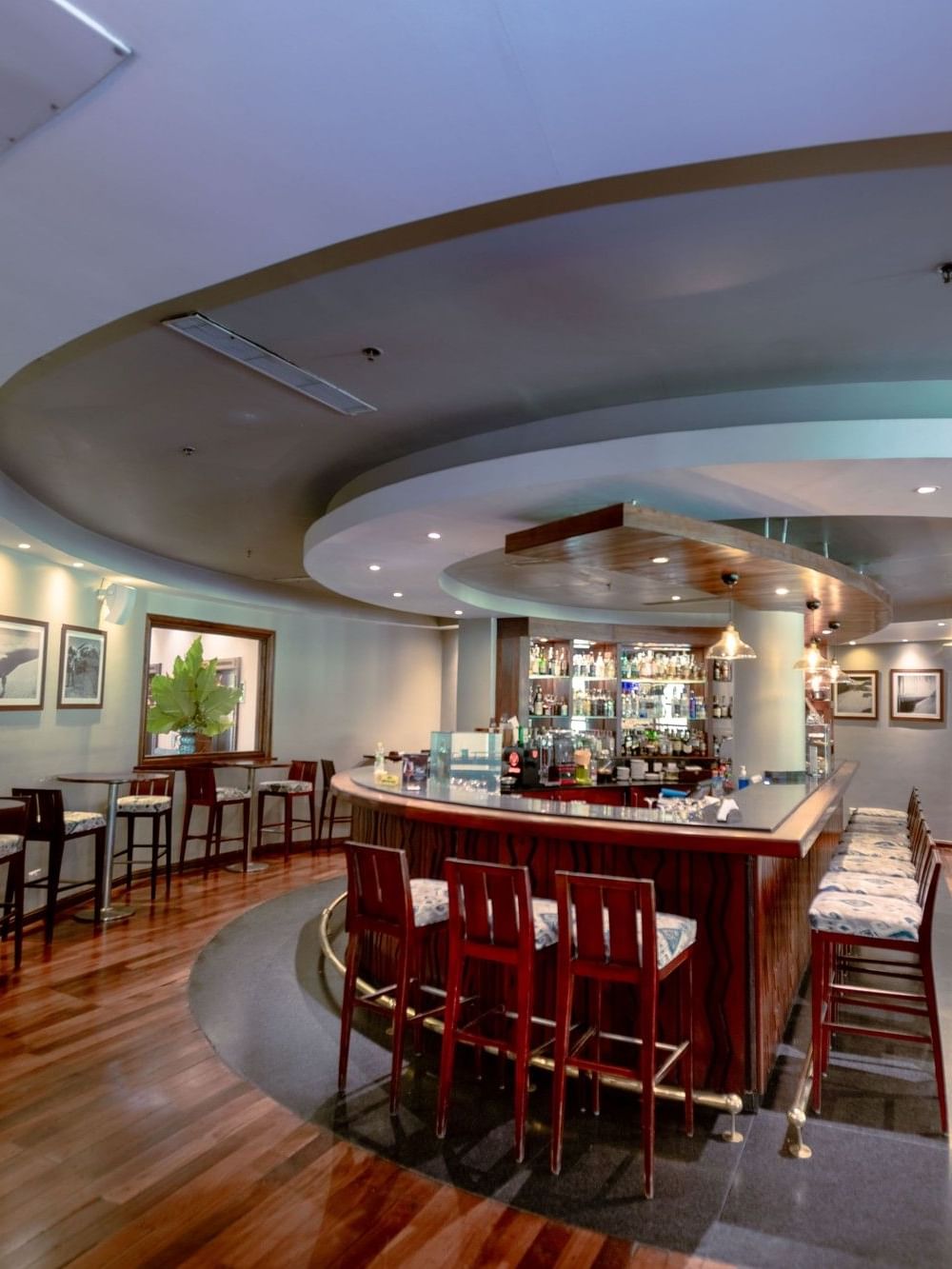 Kibo Bar and Terrace with stools, wooden floors, and a circular bar at Dar Es Salaam Serena Hotel in Dar es Salaam.