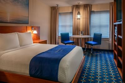 Bed with sea art above the headboard and two windows near a table in Queen City View at Harborside Inn Boston