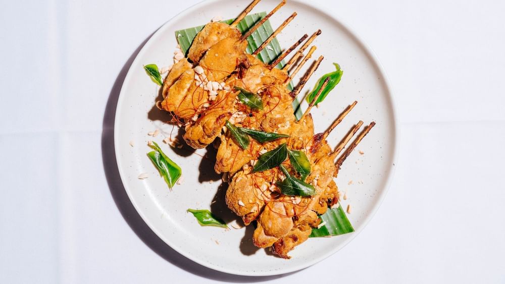 Plate of grilled skewers garnished with green leaves and peanuts served in Forest Room at Novotel Sydney Olympic Park