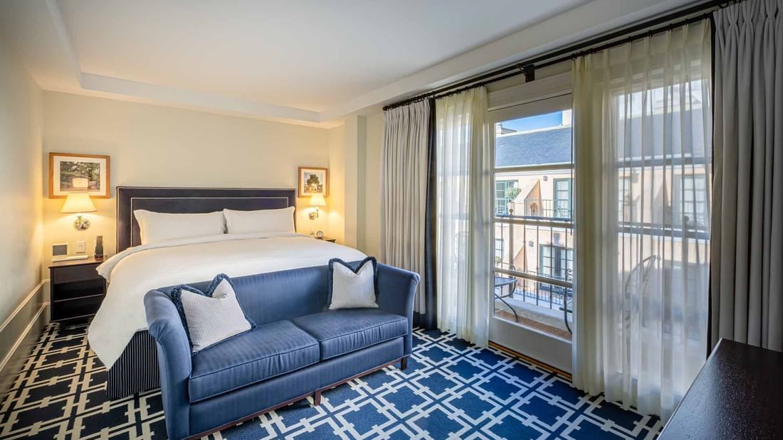 Cozy sofa by the bed in Deluxe Junior King Suite with carpetd floors and private balcony area at El Prado Hotel